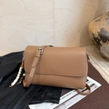 Detailed macro view of tan pebble leather crossbody bag with ethnic beaded charm on leather - Brown with Pendant