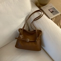 Nahaufnahme der karamellbraunen Ledertasche mit Silberschnalle auf weißem Sofa - Braun