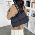Chic black quilted puffer tote bag shown on model with stylish oversized design - Black
