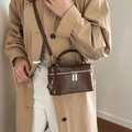Braune Lederbox-Tasche mit Silber-Reißverschlüssen und Schultergurt zu beigem Mantel - Braun