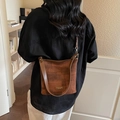 Braune karierte Beuteltasche mit Lederriemen für Damen über der Schulter getragen - Braun