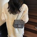 Grey quilted chain bag with turn-lock clasp worn by a model in casual setting - Black