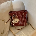 Bordeauxrode gewatteerde bucket bag met gouden ketting en teddybeertje op boekachtergrond - Rood met Hanger