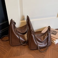 Juego de dos bolsos hobo vintage marrón oscuro con cadenas sobre un suelo de madera - Café grande