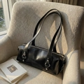 Glossy black leather Boston shoulder bag with silver studs on a beige sofa - Black