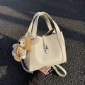 Cremefarbene Handtasche aus Leder mit Kieselstruktur, Drehverschluss und Plüschanhänger - Mit Anhänger / Cremeweiß