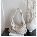 Detail of a creamy white hobo bag featuring silver rivets placed on a minimalist setup - White
