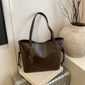 Bolso tote de cuero marrón oscuro con cordones y colgante elegante sobre libros - Café con Colgante