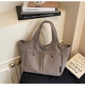 Detail der braunen Canvas-Tasche mit zwei Vordertaschen und hochwertigen Metalldruckknöpfen - Grau