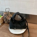 Detailed close-up of a black leather dumpling bag with drawstring bow and silver bead - Black