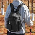 Detail of black plaid nylon backpack with mini pouch against autumn forest background - Black