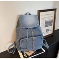 Detalle de mochila de mezclilla azul claro con cierre de cordón y bolsillo frontal con cremallera - Azul claro