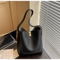 Detail of black lychee grain leather bucket bag with gold hardware in office setting - Black