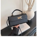 Classic black crossbody handbag with cross-grain texture and gold twist lock in lifestyle setting - Black