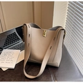 Detail of the golden twist lock and lychee-textured leather on the beige bucket bag - Gray
