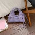 Borsa a mezzaluna viola con pieghe, fiocchi e tracolla regolabile su sfondo accogliente - Viola