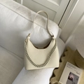 Schicke beige Hobo-Tasche mit Lychee-Struktur und dicker Kette auf weißem Sofa - Gebrochenes Weiß