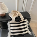 Détail d'un sac cabas en tricot rayé noir et blanc avec franges crème sur un canapé noir - Blanc