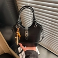 Détail d'un sac seau en cuir noir avec breloque en perles de bois et fermoir métallique - Noir