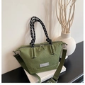 Close-up of green checkered canvas tote with black and white knotted handles - Green