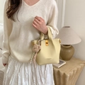 Elegant pale yellow bucket bag with lychee leather texture and plush bear charm - Yellow with Pendant