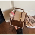 Detail eines Retro-Rucksacks mit Kontrastfarben und Plüsch-Affenanhänger auf Holzboden - Beige Mit Anhänger