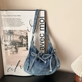 Blue denim hobo shoulder bag with decorative bows and washed finish on a minimalist background - Light Blue