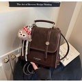 Nahaufnahme des braunen Retro-Rucksacks mit Plüsch-Anhänger und polierten Metallknöpfen - Kaffee mit Anhänger