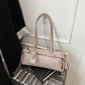 Dettaglio borsa baguette beige in ecopelle con fibbia metallica su una valigia - Grigio