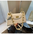 Détail d'un sac blanc en cuir texturé avec une boucle à fermoir tournant dorée - Blanc Cassé