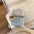 Dettaglio borsa a tracolla azzurra con fibbia d'argento e ciondolo orso su divano bianco - Blu con Pendente