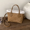 Brown monogram suede tote bag with white faux fur trim and adjustable strap on wood surface - Caramel color