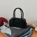Bolso de mano Boston negro clásico con cremallera plateada en un conjunto de ropa de moda - Negro