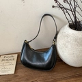 Borsa a spalla nera a mezzaluna con cerniera dorata su un tavolo in legno retrò - Stile di base / Nero