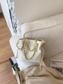 White quilted drawstring bucket bag with gold chain strap on minimalist sofa - White