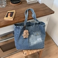 Blau-weiß gestreifte Jeans-Tragetasche mit kleinem Plüschbären-Anhänger auf Holzschemel - Blau mit Anhänger