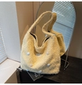Close-up of yellow fuzzy tote bag with star patches on a shelf against a round mirror - Style 2