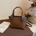 Detail showing brown pebble leather bucket bag with silver metal hardware and dry flowers - Brown