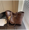 Detail of vintage brown tote bag with decorative metal buckle and colorful wooden bead tassels - Style With Charm / Coffee