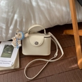 Vue détaillée du sac à main boîte crème avec fermoir rotatif argenté et breloque ours - Blanc avec pendentif