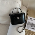 Sac boîte chic en cuir noir mat avec fermoir rotatif argenté sur un canapé blanc - Noir sans Pendentif
