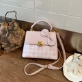 Detail of pink plaid bag with gold cat lock and decorative leather bow accent - Pink