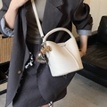 Sac seau crème tendance avec nœud léopard et breloque cœur porté par un mannequin - Beige Avec Charme