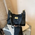 Borsa retrò in denim nero con chiusura girevole dorata e catena su una valigia - Nero