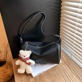 Zwarte kussen-tas van leer met pluche beer hanger op een houten tafelblad - Met Hanger / Zwart