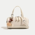 Creamy white cylindrical Boston bag with textured fabric, leather trim and plush charms - Off White