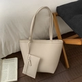 Detail van beige lederen draagtas met bijpassend etui met rits op een houten stoel - Wit