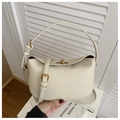 Detailansicht der cremefarbenen Eimer-Tasche mit Lychee-Narbung und goldenem Drehverschluss - Milchweiß Ohne Anhänger
