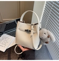Detailed view of white pebble leather bucket bag with silver lock and plush bunny charm - Cream White With Pendant