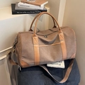 Large brown canvas travel bag with leather trim on a vintage wooden stool - Brown